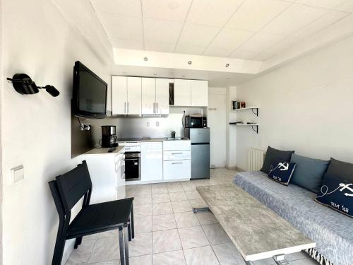 un salon avec un canapé et une cuisine dans l'établissement T2 BORD DE MER vue plages WIFI climatisé parking inclus, à La Ciotat
