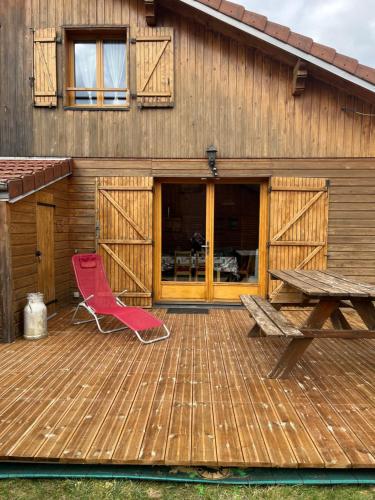a wooden deck with a picnic table and a red chair at Chalet exposition plein sud in Xonrupt-Longemer