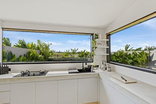a kitchen with white cabinets and a large window at Villa Luxfield - Peaceful minimalist 2BR villa with Big garden and Views in Cemagi