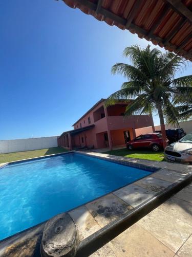 una piscina davanti a una casa con una palma di Casa Taíba a São Gonçalo do Amarante