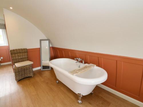 een badkamer met een wit bad en een stoel bij Fladda in Oban