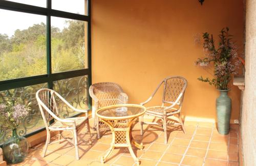a patio with wicker chairs and a table and a window at Rural Coliving in Pontevedra