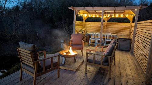 a wooden deck with chairs and a table with a fire at Rose Cottage in Ledbury