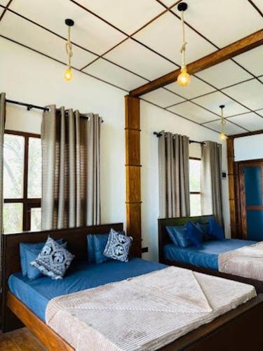 a bedroom with two beds with blue pillows at Royal Lodge Belihuloya in Belihul Oya