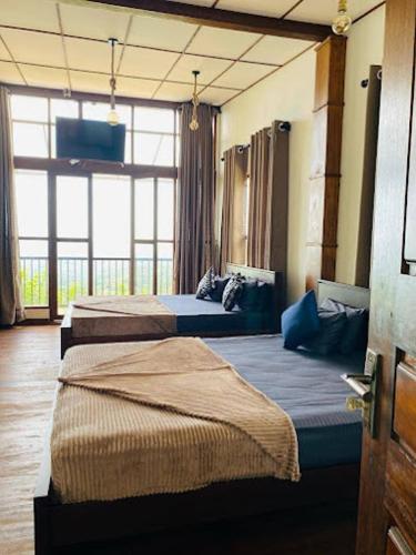 a hotel room with two beds and a large window at Royal Lodge Belihuloya in Belihul Oya
