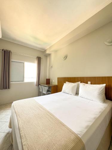 a bedroom with a large white bed with a window at Ilha Porchat Hotel in São Vicente