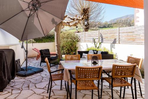 un patio avec une table, des chaises et un parasol dans l'établissement Pays Basque Gite Munhoa, à Anhaux