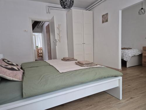 Spodnja IdrijaにあるHoliday Home Milaの白いベッドルーム(緑のシーツが敷かれたベッド付)