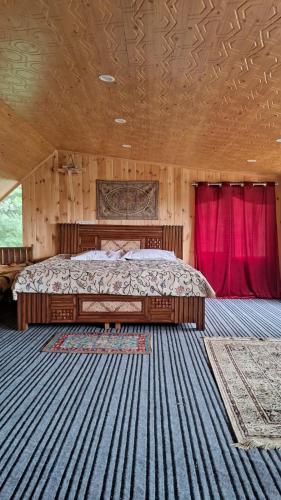 a bedroom with a bed in a room with red curtains at Himalayan Huts in Srinagar