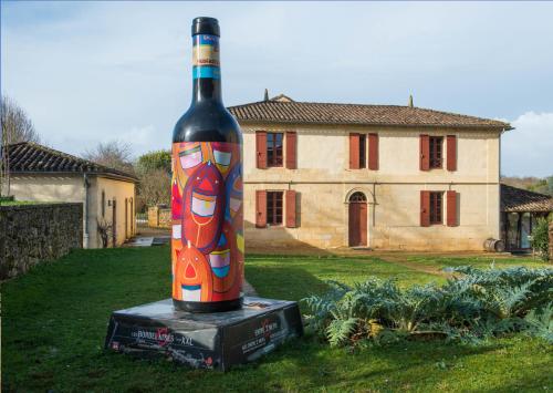 a bottle of wine sitting on a box in front of a house at Atena Bordeaux Sud Est Créon - Vélo Friendly in Créon