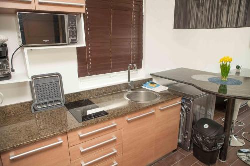a small kitchen with a sink and a microwave at Midtown Apto in Town Center in Río Hato
