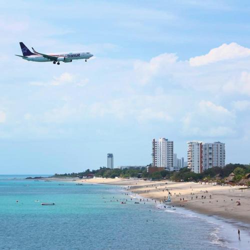 an airplane flying over a beach with people and buildings at Midtown Apto in Town Center in Río Hato