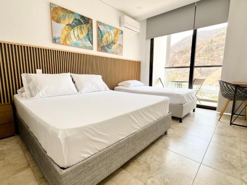 a bedroom with two beds and a large window at Apartasuites VITA 945 RODADERO - By Bedviajes in Santa Marta