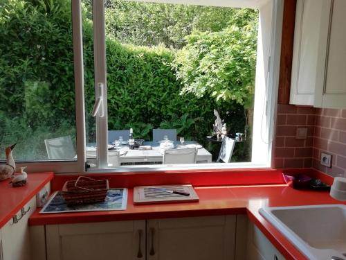 une cuisine avec un comptoir rouge et une fenêtre dans l'établissement Havre de paix entre mer et forêt, à Ploumilliau