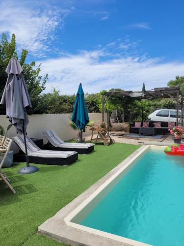 une piscine avec des chaises et des parasols à côté d'une piscine dans l'établissement Maison de vacances avec piscine près de Montpellier, à Saint-Drézéry