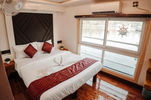 a bedroom with a bed and a large window at Marvelous Boathouse in Alleppey