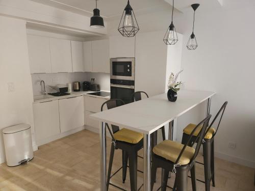 une cuisine avec une table et des chaises dans une pièce dans l'établissement Centre Antibes Le Piadon 3 pièces neuf Parking, à Antibes