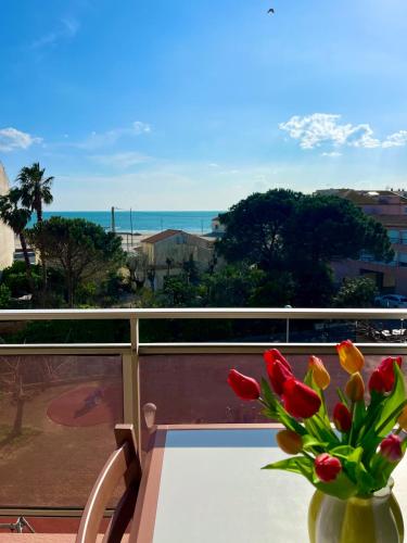 un vase de fleurs posé sur une table sur un balcon dans l'établissement Studio cabine vue mer, au Grau-dʼAgde
