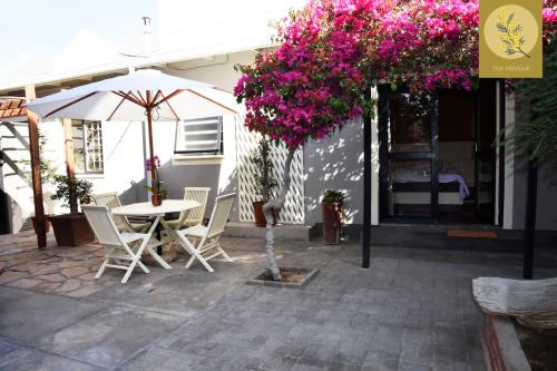 a patio with an umbrella and a table and chairs at Le Mimose Escape - Swakopmund Namibia in Swakopmund