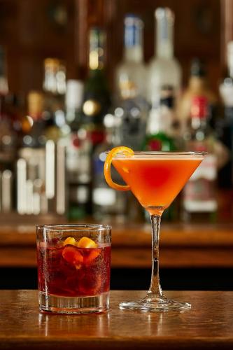 two cocktails sitting on a wooden table in a bar at Macdonald Elmers Court Hotel in Lymington