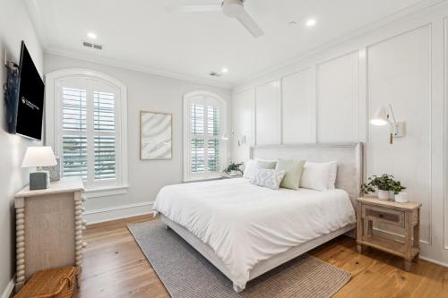 a white bedroom with a large bed and windows at The Chateau - By Charleston Vacays in Charleston