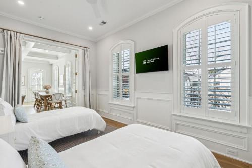 a white bedroom with two beds and a table at The Chateau - By Charleston Vacays in Charleston