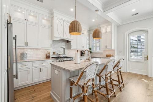 a kitchen with white cabinets and a kitchen island with chairs at The Chateau - By Charleston Vacays in Charleston
