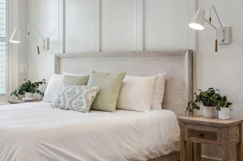 a white bedroom with a white bed with pillows at The Chateau - By Charleston Vacays in Charleston
