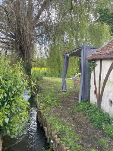a gazebo next to a stream in a garden at Gîte pieds dans l Epte prêt de Giverny in Gasny