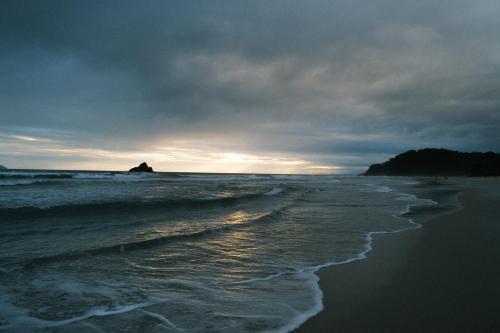 a beach with a cloudy sky and the ocean at Hiu Hotel in Juquei