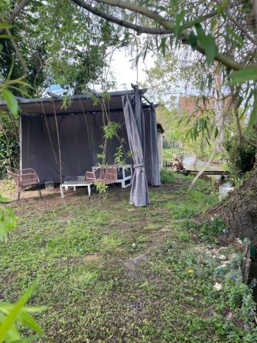 a tent with a bench and an umbrella in a yard at Gîte pieds dans l Epte prêt de Giverny in Gasny