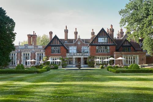 a large brick house with a large yard at Macdonald Elmers Court Hotel in Lymington
