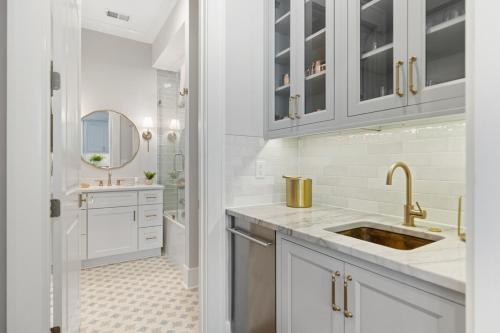 a white bathroom with a sink and a mirror at The Cavalla- private pool & roof top deck in Charleston