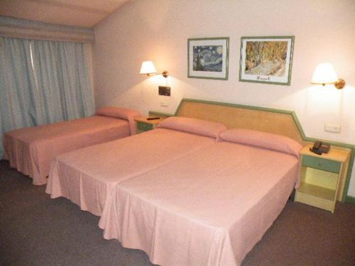 a hotel room with two beds with pink sheets at Puente Romano in Ourense