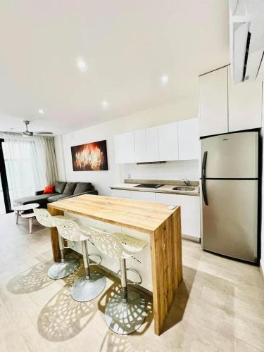 a kitchen with a wooden table and a refrigerator at Maravilloso Pent House en 5th Avenida nuevo en plataforma in Playa del Carmen