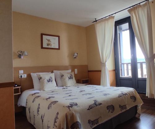 a bedroom with a bed and a large window at Hotel Restaurant La Clairiere in Chambon-sur-Dolore