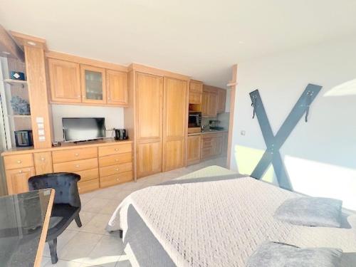 - une chambre avec un lit, une télévision et des placards en bois dans l'établissement Studio 4, Héliopolis D au village naturiste, au Cap d'Agde