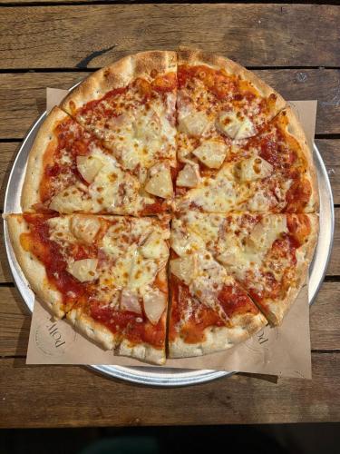 a pizza on a plate on a wooden table at The Prince of Waterloo - Boutique Guest Rooms in Winford