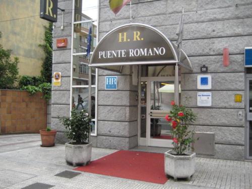 a building with two potted plants in front of a store at Puente Romano in Ourense