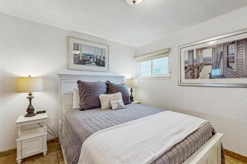 ein Schlafzimmer mit einem Bett, einer Lampe und zwei Fenstern in der Unterkunft Cozy Carmet Cottage in Bodega Bay