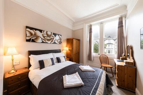 a bedroom with a bed and a desk and a window at The Annan Hotel in Llandudno