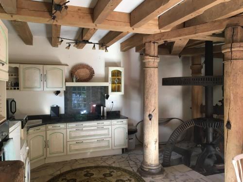 a kitchen with white cabinets and a wooden ceiling at Gite du Moulin Vieux in Vigoulant