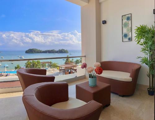 a living room with chairs and a view of the beach at Stunning Bay View Condo, Pool in Santa Bárbara de Samaná
