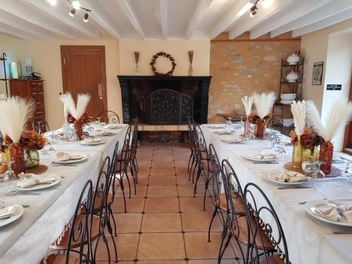 une salle avec de longues tables et chaises et des nappes blanches dans l'établissement Gite - Le Domaine des Hallais, à Saint-Pierre-sur-Erve