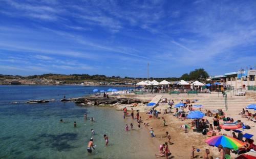 a crowd of people on a beach with umbrellas at Sea View 2 Bed Apartment close to beach Hpi6768 in Il-Maħsel