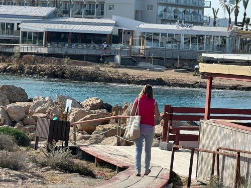 a woman walking down a boardwalk next to a river at Big house in center of protaras, near beach in Protaras