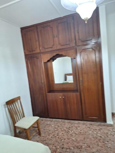 a room with a wooden cabinet with a mirror and a chair at Big house in center of protaras, near beach in Protaras