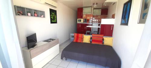 Cette petite chambre comprend un lit avec des oreillers colorés. dans l'établissement Studio 729, Port Nature 7 au village naturiste, au Cap d'Agde