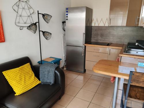 une cuisine avec un canapé noir et un réfrigérateur dans l'établissement Appartement T2 sur cour nantaise, à Rezé