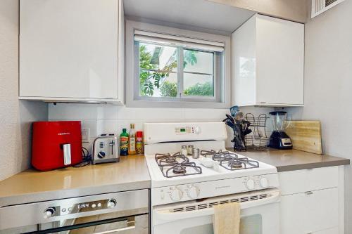 a white kitchen with a stove and a window at Sordid Lives Condo Permit# 3202 in Palm Springs